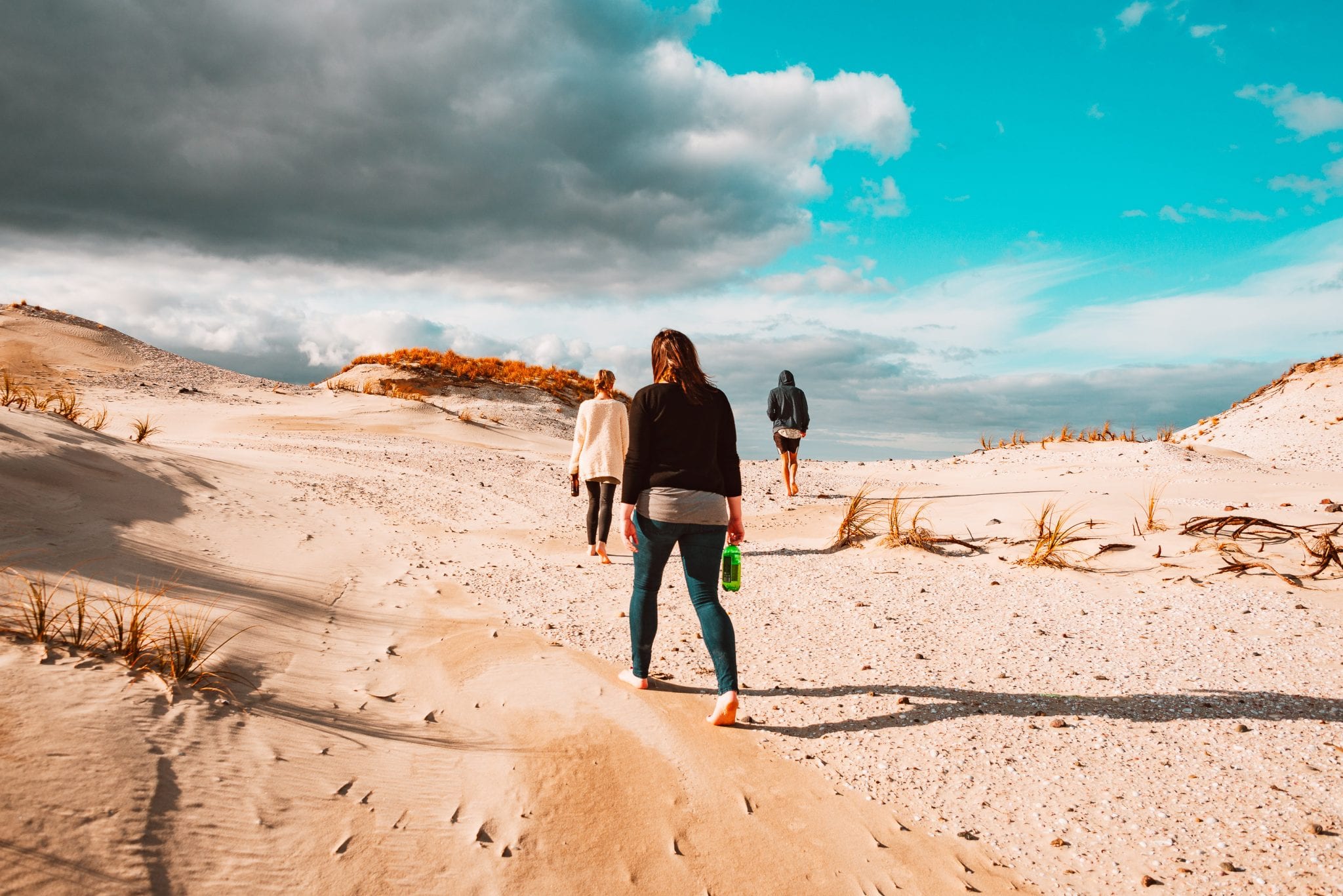 friends walking across the sand dunes at mangawhai heads