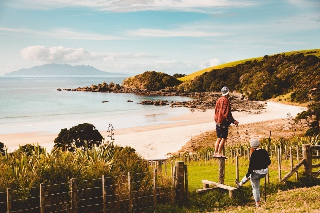 friends crossing a fence at tawharanui regional park