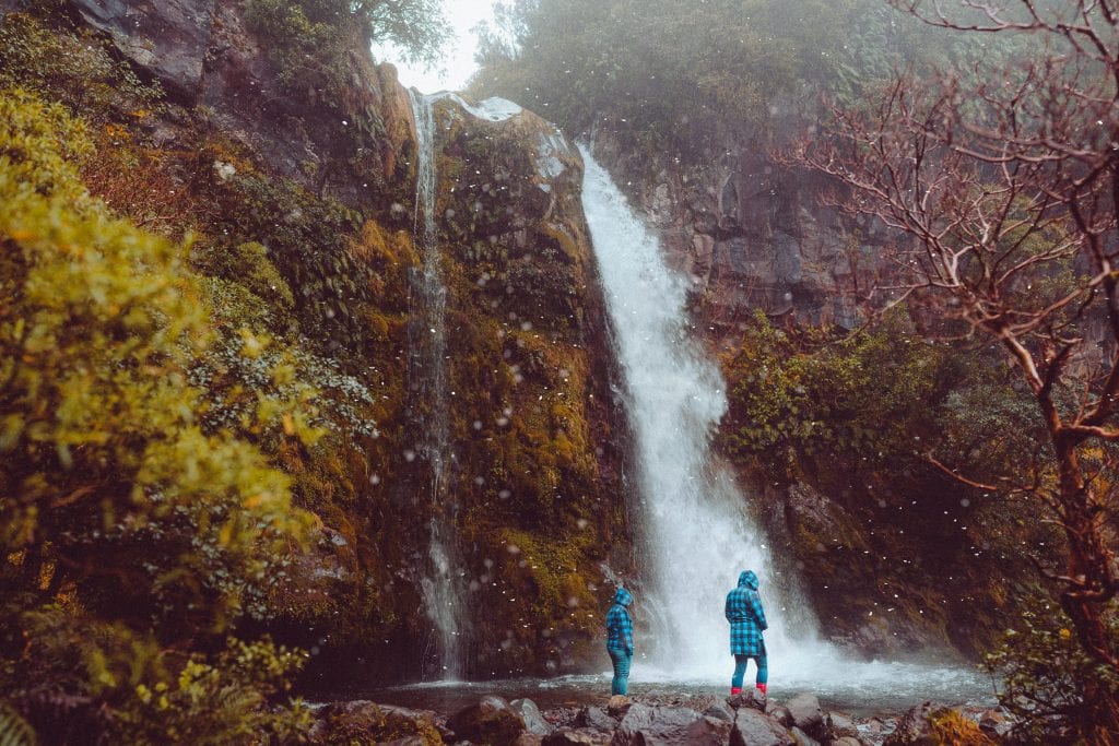 snow falling on two friends at dawson falls in taranaki