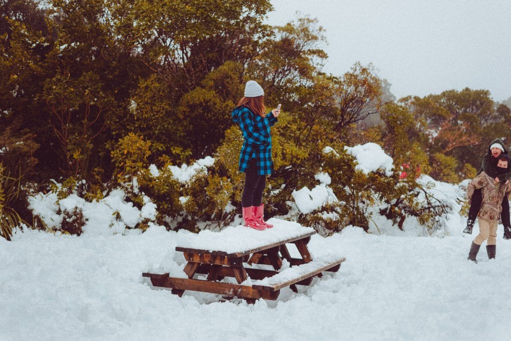 a woman stands on a snow covered table on mount taranaki